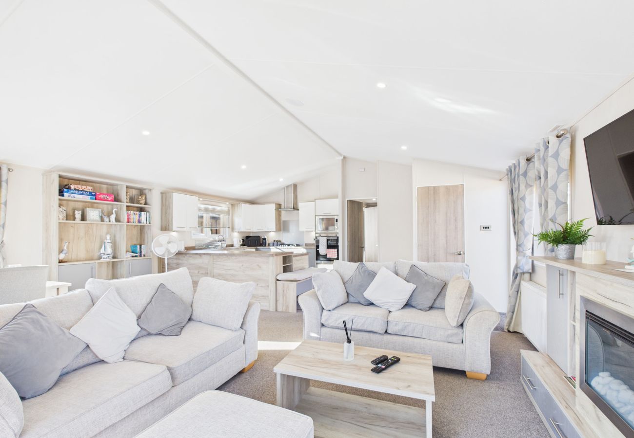 Bright holiday lounge with a grey sofa and wall-mounted TV.