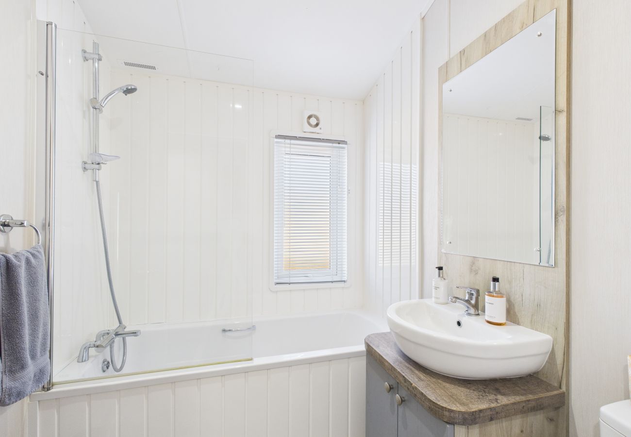White bathroom suite with a bathtub and glass shower screen.
