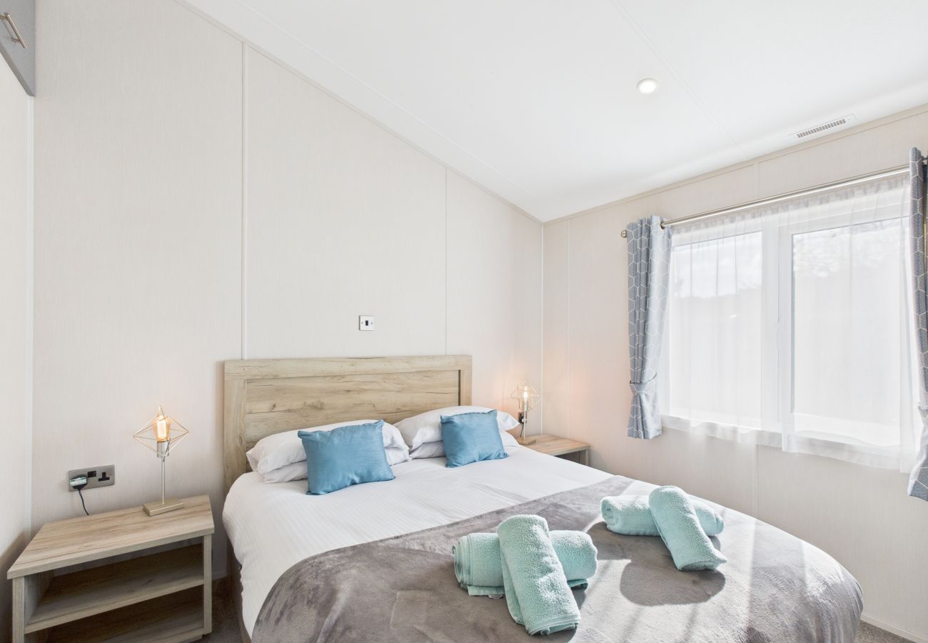 Large bed with blue cushions in a bright, modern lodge bedroom.