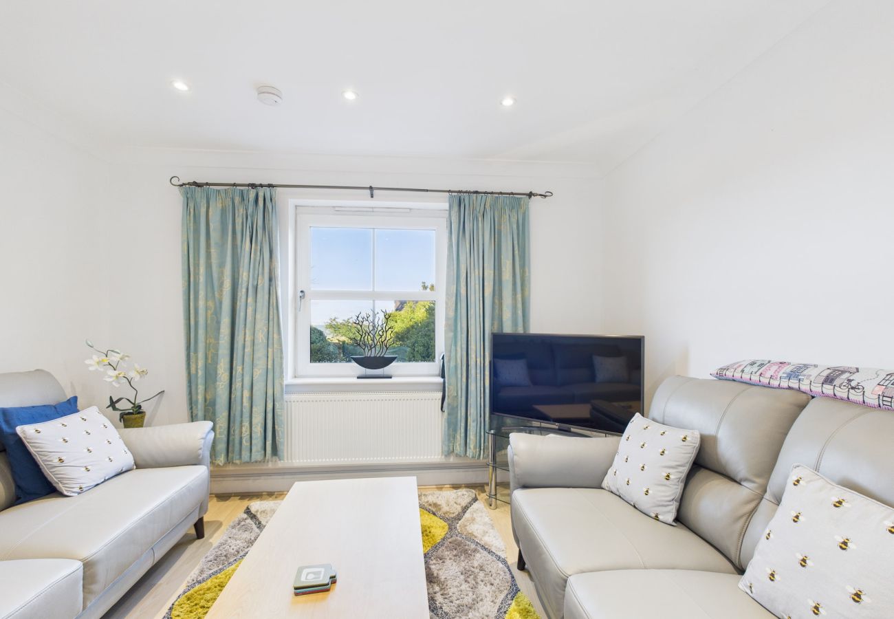 A coastal-themed lounge with grey sofas and a large window with beach views.