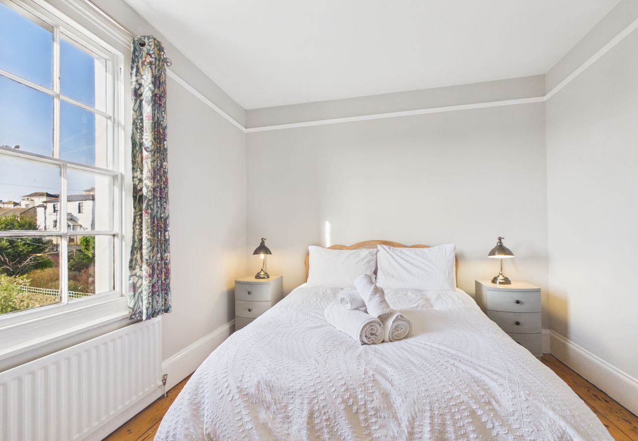 Comfortable double bed with bedside lamps in a character-filled room.