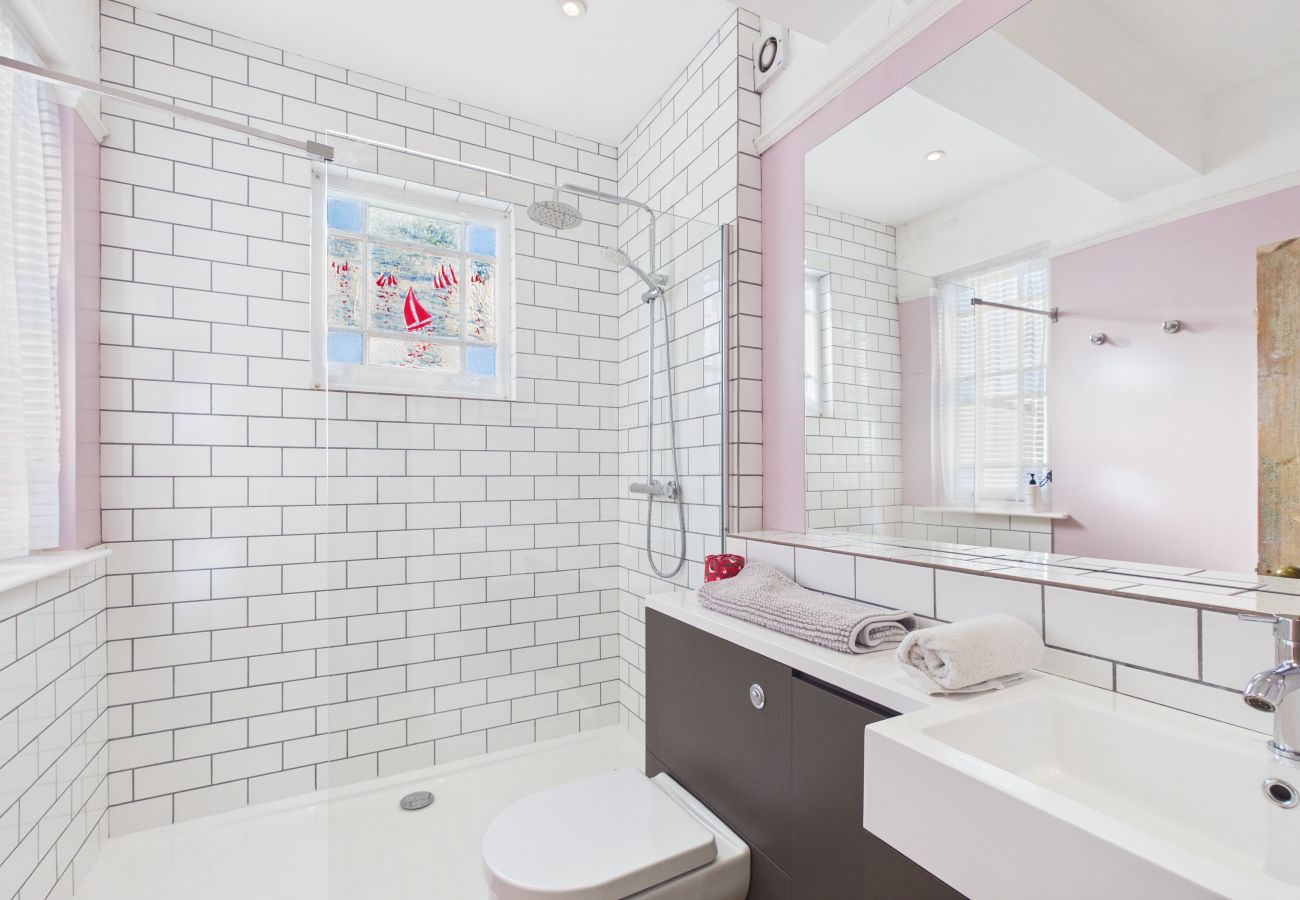 Sleek bathroom with a large walk-in shower and modern white tiling.