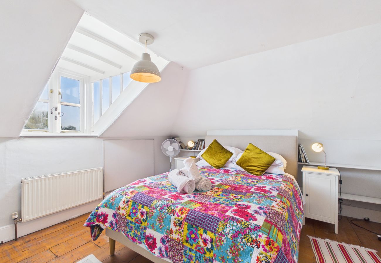 King-size bed with white linens in a bright top floor bedroom.