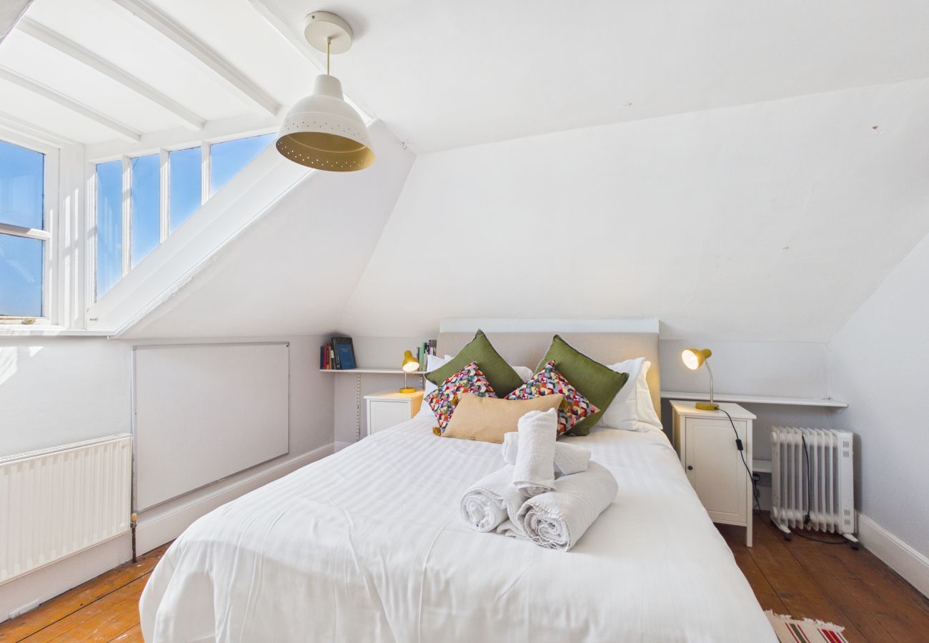 King-size bed with white linens in a bright top floor bedroom.