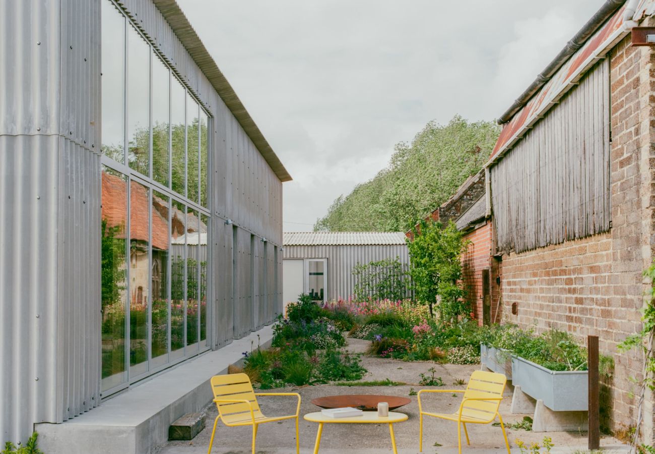 Outdoor dining table and chairs on a paved patio outside a modern barn conversion.