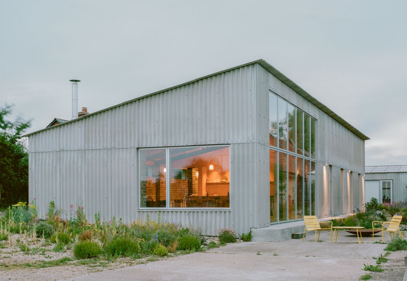 Wide shot of South Barn holiday home showing the architectural metal cladding and surrounding greenery.